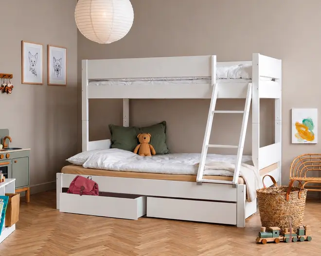 Hvid køjeseng i træ med solid ramme og skrå stige for nem adgang til øverste køje. Nederste køje har et bredt soveområde med en grøn pude og en bamse for ekstra hygge. Under sengen er der to rummelige udtræksskuffer, perfekte til opbevaring af legetøj, sengetøj eller tøj. Designet er moderne og minimalistisk, velegnet til børneværelset eller gæsteværelset.
