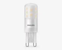 En kompakt LED-pære med cylindrisk form, mat finish og synlige interne LED-chips arrangeret i to lodrette rækker. Soklen er en G9-stik med to ben, hvilket gør den nem at installere i kompatible fatninger. Pæren har 'PHILIPS' trykt på siden, hvilket angiver producenten.