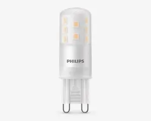 En kompakt LED-pære med cylindrisk form, mat finish og synlige interne LED-chips arrangeret i to lodrette rækker. Soklen er en G9-stik med to ben, hvilket gør den nem at installere i kompatible fatninger. Pæren har 'PHILIPS' trykt på siden, hvilket angiver producenten.