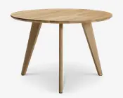 Rundt bord med en glat, lys træfinish. Har et minimalistisk design med tre skråtstillede ben for stabilitet. Bordpladen har et diskret træmønster, og kanterne er let affasede for et elegant udtryk. Benene er tilspidsede, hvilket giver bordet et moderne og stilrent udseende.