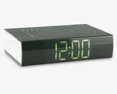 Rektangulært digitalur med sort top og sider, der har et stort, letlæseligt grønt LED-display, som viser tiden '12:00'. Overfladen har en mat finish, og uret har et minimalistisk, moderne design uden synlige knapper eller betjeningselementer på fronten.