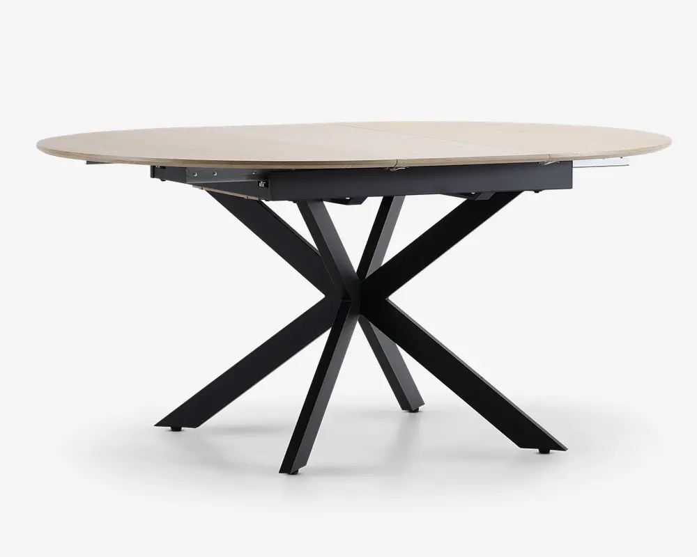 Et moderne bord med en lys, rund bordplade med glat overflade. Bordets ben er lavet af sort metal og er arrangeret i et markant krydset stjernemønster, hvilket giver både stabilitet og et moderne udtryk.