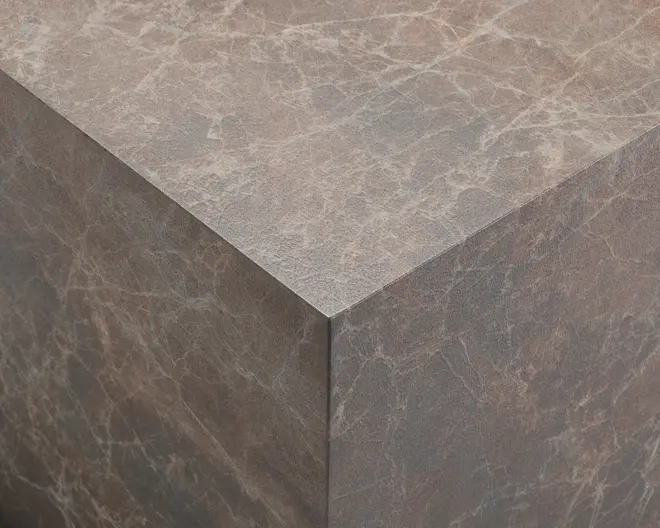 Nærbillede af en kube med en brun marmorlignende overflade. Teksturen har naturlige årer i lysere nuancer, hvilket giver et realistisk stenlook. Kanterne er skarpe, og overfladen ser glat og mat ud.