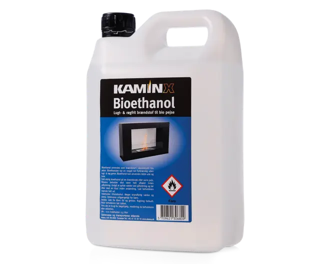 Stor hvid plastdunk med sort skruelåg og indbygget bærehåndtag for nem transport. Forsiden har en sort og blå etiket med mærket "KAMIN X" og produktnavnet "Bioethanol." Etiketten viser også et billede af en pejs, hvilket indikerer anvendelsesområdet, samt sikkerhedsadvarsler som et brandfarligt-symbol. Dunken er beregnet til opbevaring og udhældning af flydende brændstof, med tydelig mærkning af sikkerheds- og brugsanvisninger.