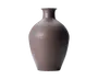 En mat mørkebrun keramikvase med smal, let udadbuet hals, afrundede skuldre og en smal bund, vist på sort baggrund.