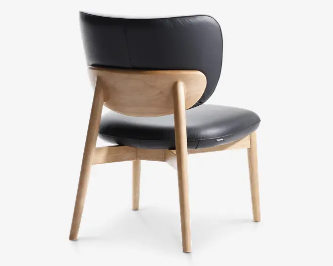 Stol med buet træramme i lys naturfinish, kombineret med polstret sæde og ryglæn betrukket med glat sort læder. Ryglænet er rundet og går delvist rundt om siderne for ekstra komfort. Benene er let skråtstillede, hvilket giver stabilitet og et moderne udtryk.
