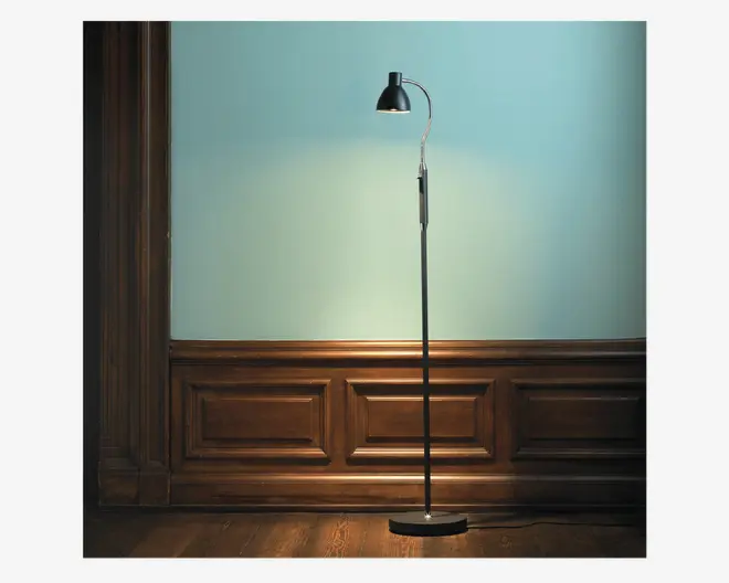 En høj, slank standerlampe med en rund, flad fod og en buet, justerbar hals. Lampen har en sort metalfinish og en kuppelformet skærm, der giver fokuseret lys nedad. Designet er minimalistisk og moderne, velegnet til læsning eller stemningsbelysning.