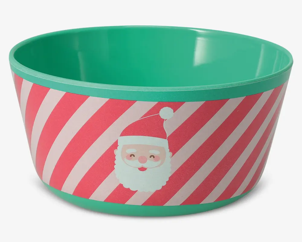 En rund skål med turkis inderside og kant. Ydersiden har et festligt design med diagonale lyserøde og hvide striber samt et tegnet julemandsansigt med rød hue. Skålen har en glat overflade og et muntert juletema.