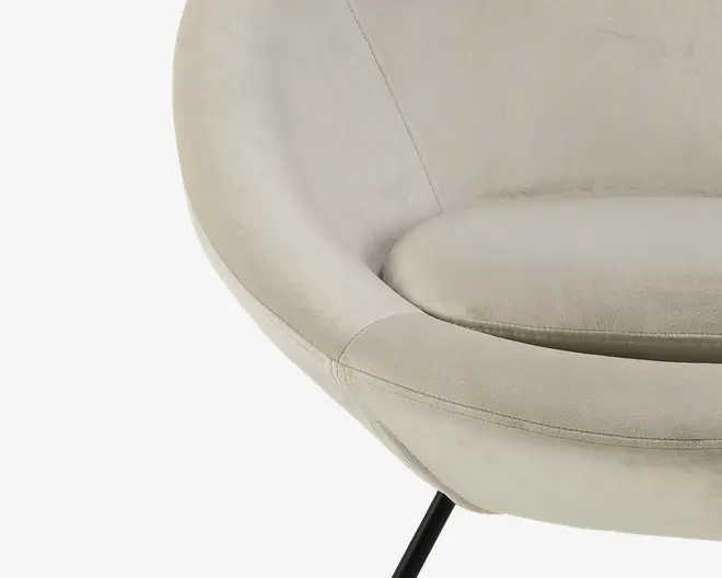 Nærbillede af en moderne stol med rund, skålformet siddeflade og blødt, lysebeige betræk. Sædepuden er tyk og blød for ekstra komfort. Stolen har diskrete syninger langs kanterne og står på slanke, sorte metalben.