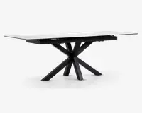 Rektangulært bord med en glat, hvid marmoreret eller marmorlignende bordplade og en markant sort metalbase. Basen har et kantet, stjerneformet design med flere ben, der stråler ud fra et centralt punkt, hvilket giver både stabilitet og et moderne, skulpturelt udtryk. Bordet har rene linjer og en nutidig stil.