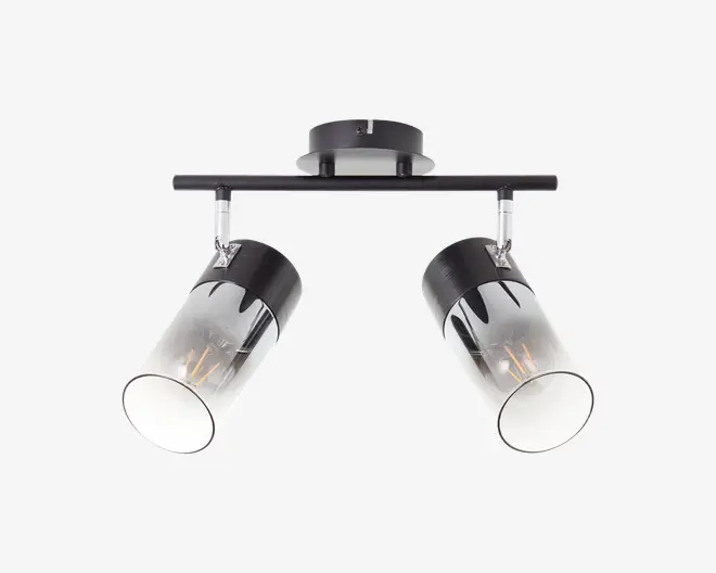 Loftmonteret armatur med to justerbare cylindriske spotlys. Hver spot har en sort metalbase og en klar glasafskærmning med et dekorativt sort drypmønster øverst. Armaturet er fastgjort til en rektangulær metalstang, hvilket gør det muligt at vinkle spotlysene efter behov. Moderne og stilrent design, der passer til nutidige indretninger.