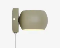Væghængt lampe med mat olivengrøn finish og en rund, trommeformet skærm. Lampen har et enkelt, moderne design med en synlig skrue på monteringspladen og en ledning, der går ud fra bunden. Skærmen leder lyset nedad og giver en fokuseret belysning.