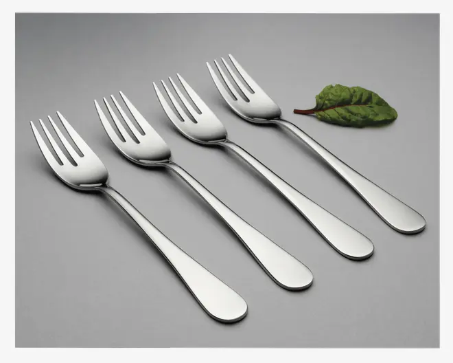 Sæt med fire polerede gafler i rustfrit stål med et enkelt, moderne design. Hver gaffel har tre brede tænder og et glat, let buet skaft med afrundet ende. Overfladen er blank og reflekterende, og skaftet er uden dekoration eller mønster. Gaflerne ligger på række på en ensfarvet, lysegrå baggrund, og øverst til højre ligger et enkelt grønt blad som dekoration.