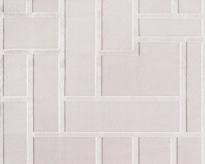 Billedet viser et stof med et geometrisk mønster bestående af rektangulære og kvadratiske former. Hver form har en forskellig, diskret tekstur, såsom sildebensmønster, net og diagonale linjer, alle i en lys beige eller off-white farve. Kanterne mellem formerne er let hævede, hvilket giver stoffet et struktureret og tredimensionelt udseende.