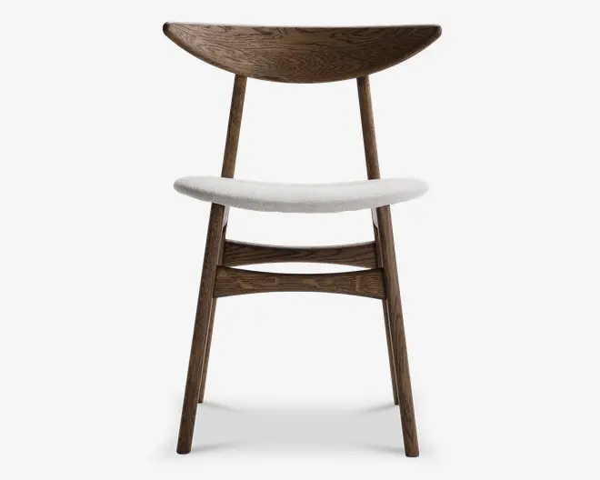 Stol med buet, bred ryglæn i træ med synlig træstruktur, skråtstillede træben og hvidt polstret sæde. Designet er minimalistisk og moderne med en solid ramme og komfortabel, støttende ryg.