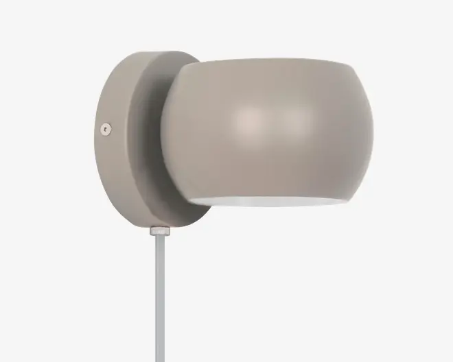 En moderne vægmonteret lampe med mat taupe-finish. Lampen har en rund, skålformet skærm, der er fastgjort til en cirkulær base. Designet er minimalistisk med en glat overflade og uden synlige dekorative elementer. En ledning går ud fra bunden af basen.