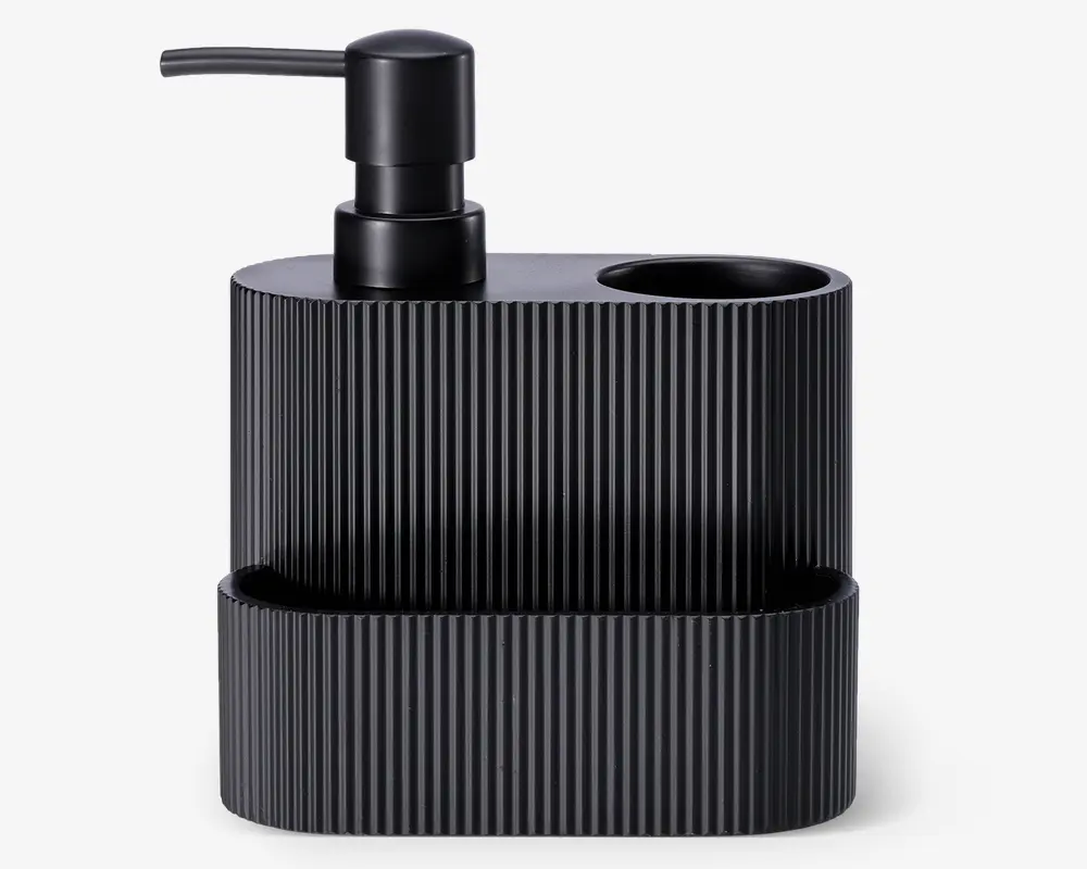 Mat sort organizer i sort med lodret rillet overflade, indbygget pumpe-dispenser, et rundt rum til for eksempel tandbørster og en frontbakke til småting. Moderne, minimalistisk design, der passer til badeværelse eller køkken.