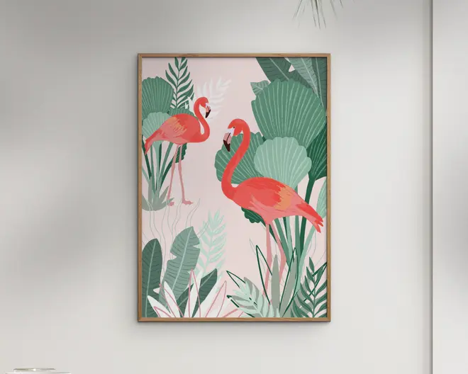 Indrammet kunstværk med en illustration af to lyserøde flamingoer, der står blandt store, stiliserede grønne tropiske blade på en blød pastelrosa baggrund. Flamingoerne er tegnet i levende nuancer af pink og orange, hvor den ene står i forgrunden og den anden i baggrunden, hvilket giver dybde til motivet. Rammen er enkel og i lyst træ, hvilket understreger det friske og moderne udtryk i billedet.