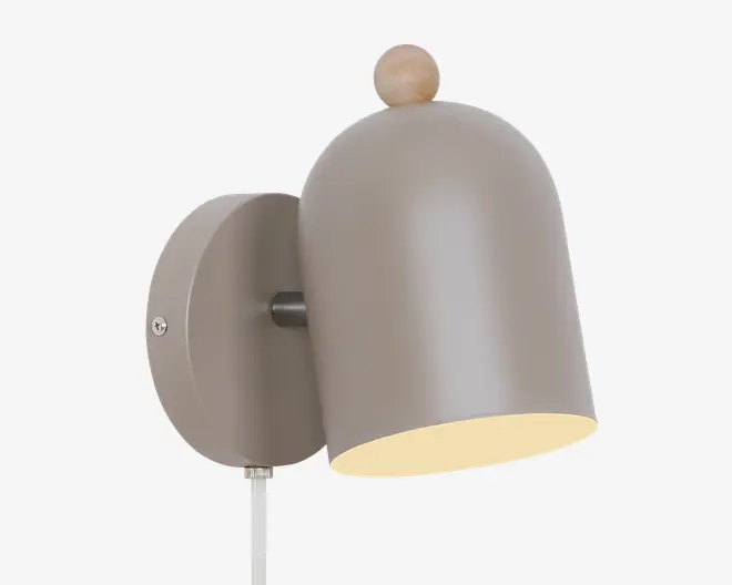 Væghængt lampe med mat taupefarvet kuppelformet skærm, rund vægplade og lille træfarvet knop på toppen, vist vinklet nedad med en varm lys inderside.