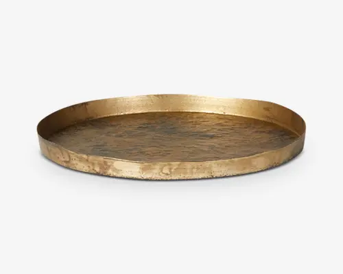 Rund bakke med en let forhøjet kant, lavet af metal med en hamret tekstur. Bakken har en gylden finish, hvilket giver den et rustikt og elegant udseende. Overfladen har diskrete variationer i farve og tekstur, hvilket bidrager til et håndlavet look.