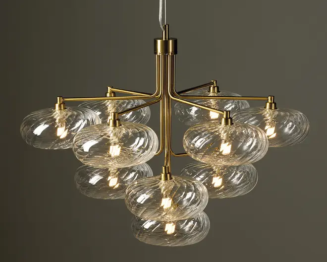 En moderne lysekrone med en central stamme i guldfarvet metal og otte vandrette arme, hvor hver arm bærer to klare, teksturerede glasskærme. Glasskærmene er runde og let flade med et diskret hvirvelmønster, og hver skærm indeholder en synlig glødepære, der udsender et varmt lys. Designet er elegant og moderne med en symmetrisk opbygning og materialer af høj kvalitet.