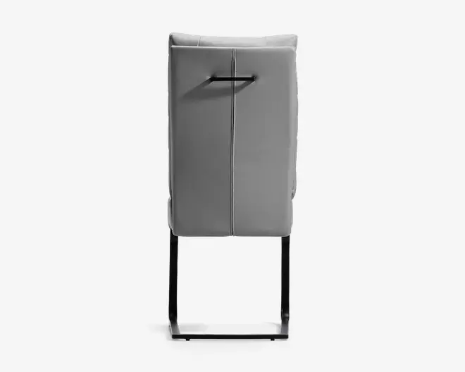 Høj, grå, rektangulær taske-lignende genstand med polstret frontpanel, lodret søm i midten, sort håndtag øverst og sort åben metalramme i bunden.