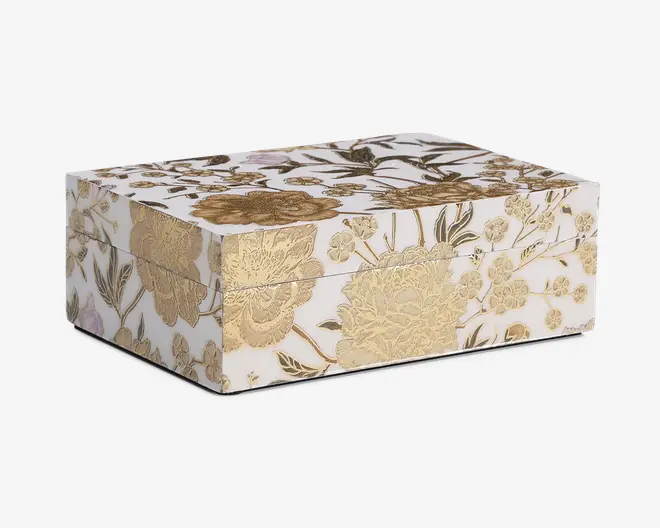 Rektangulær æske med blank hvid overflade, dekoreret med indviklede guldfarvede blomstermønstre på alle synlige sider. Blomsterne er præget, hvilket giver et tekstureret og luksuriøst udseende. Æsken har et hængslet låg og skarpe, rene kanter, hvilket gør den velegnet til dekoration eller opbevaring.