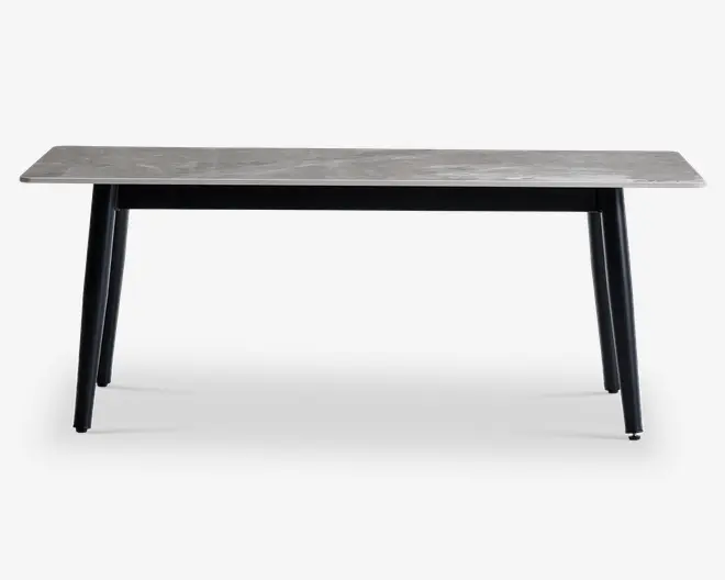 Rektangulært bord med en lysegrå bordplade med træstruktur og fire skråtstillede sorte ben. Designet er minimalistisk og moderne med rene linjer og en glat overflade. Benene er let tilspidsede, hvilket giver bordet et elegant udtryk.