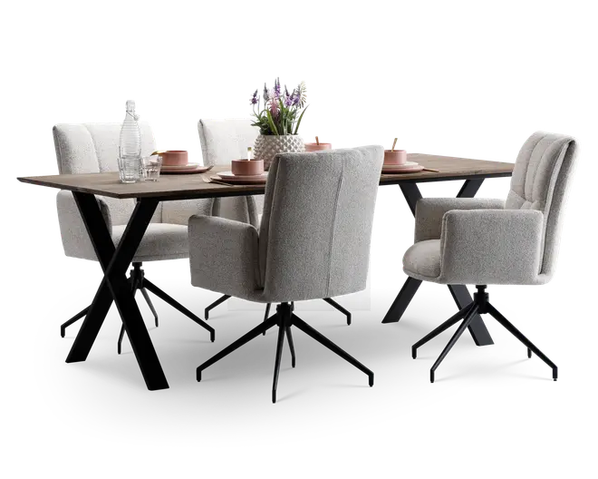 Moderne spisesæt med et rektangulært bord i træ og skrå sorte metalben. Sættet inkluderer fire polstrede stole i lysegråt stof, alle med armlæn og drejefod. Bordet er dækket med lyserøde keramiktallerkener, skåle og kopper samt klart glas og en dekorativ vase med lilla blomster.