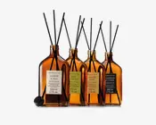 Fire ravfarvede glasduftdiffusorer med lange sorte pinde, hver med en rektangulær etiket og markering på 500 ml, sat på række.