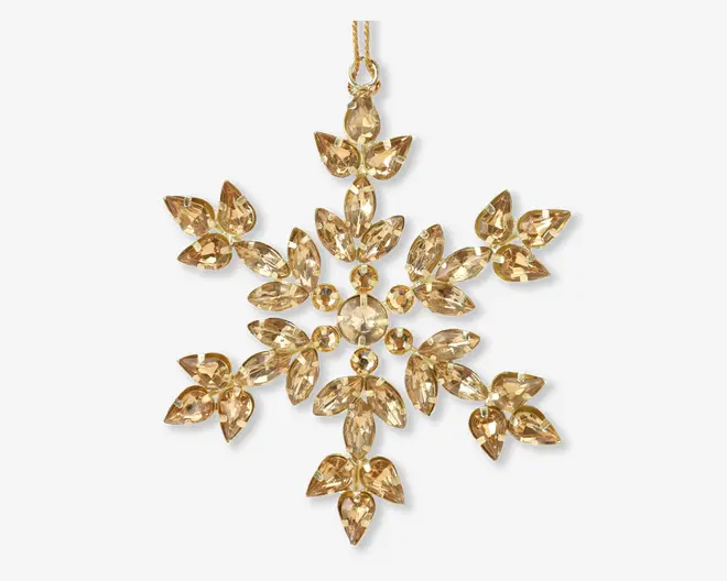Guldfarvet ornament formet som en snefnug, dekoreret med mange facetslebne, marquise-formede krystaller arrangeret i et symmetrisk mønster. Krystallerne er indfattet i en metalramme, hvilket giver et funklende og elegant udtryk. Ornamentet har en lille løkke øverst til ophængning.