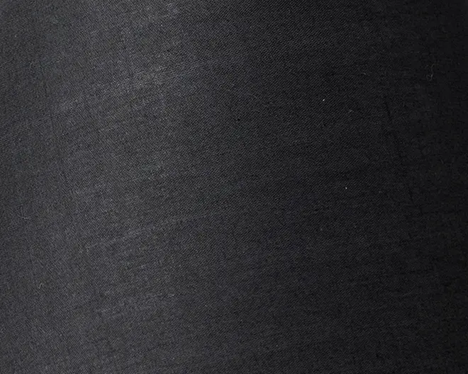 Nærbillede af et glat, mat sort stof med en diskret vævet struktur. Materialet fremstår tæt vævet og ensartet uden synlige mønstre eller udsmykninger.