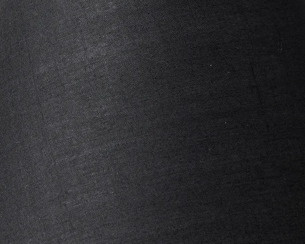 Nærbillede af et glat, mat sort stof med en diskret vævet struktur. Materialet fremstår tæt vævet og ensartet uden synlige mønstre eller udsmykninger.