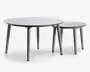 Sæt med to runde borde i minimalistisk design, med glatte, flade overflader og slanke, tilspidsede ben. Bordene har forskellige størrelser, så det mindre bord kan skubbes delvist ind under det større for fleksibel placering. Begge borde har en mat finish og et moderne, neutralt farveskema.