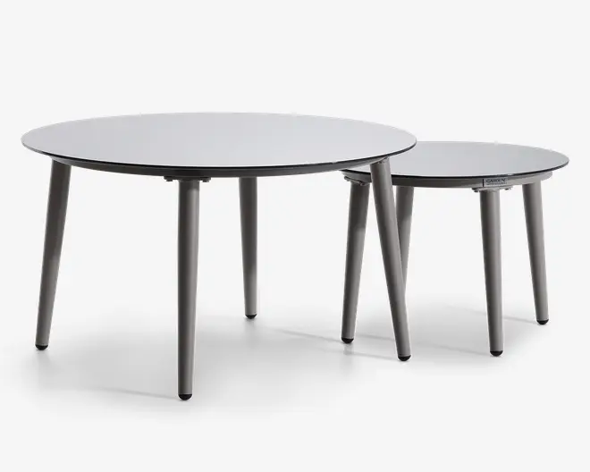 Sæt med to runde borde i minimalistisk design, med glatte, flade overflader og slanke, tilspidsede ben. Bordene har forskellige størrelser, så det mindre bord kan skubbes delvist ind under det større for fleksibel placering. Begge borde har en mat finish og et moderne, neutralt farveskema.