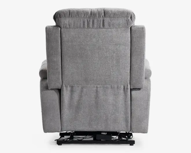 Billedet viser bagsiden af en grå polstret reclinerstol. Stolen har en polstret nakkestøtte og brede armlæn samt en glat, flad rygpanel. Stoffet ser ud til at være et blødt, tekstureret materiale. Nederst på stolen ses nogle synlige metal- og elektriske komponenter, hvilket indikerer, at den muligvis har en elektrisk recline-funktion.