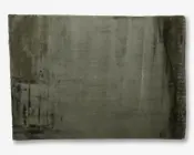 Rektangulært tæppe i en afdæmpet olivengrøn farve med et let slidt, vintage udseende. Overfladen har diskrete nuancer og teksturvariationer med mørkere felter og falmede områder, især langs kanterne og i det ene hjørne. Luven ser blød og fyldig ud, hvilket giver tæppet et hyggeligt og indbydende udtryk.