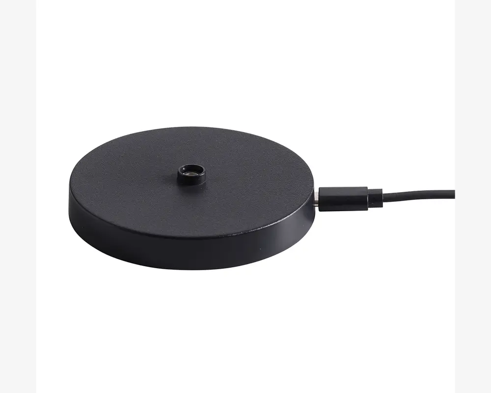 En rund, flad, sort base med mat overflade, der har et centralt gevindhul til montering. Basen er forbundet med et strømkabel på siden, hvilket indikerer, at den er elektrisk drevet eller giver elektrisk forbindelse. Designet er minimalistisk og moderne.
