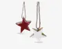 To stjerneformede ornamenter med rustikt udseende, hver med et kraftigt, tredimensionelt design. Den ene stjerne er malet i dyb rød, og den anden er malet hvid, begge med synlige trækanter for et slidt look. Hver ornament hænger i en enkel brun snor, velegnet til ophængning på et træ eller som dekorative elementer.