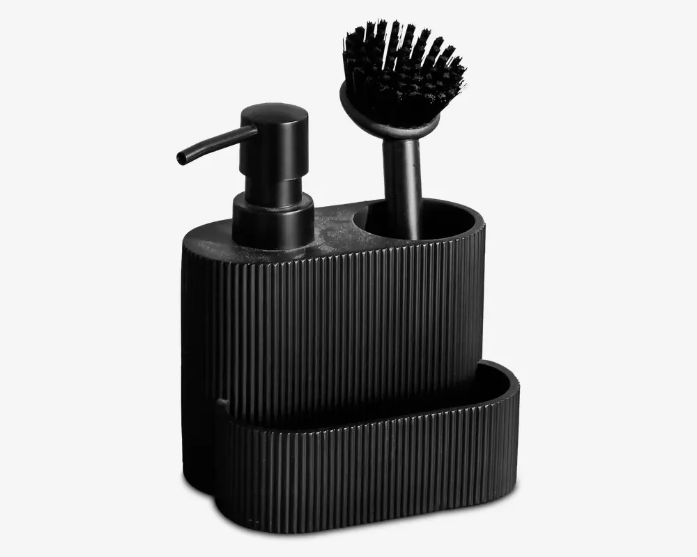 En moderne, mat sort køkkenorganizer med rillet overflade. Den har en pumpe til sæbe, et rum med en opvaskebørste med sorte børstehår og en åben frontsektion til opbevaring af svampe eller andre rengøringstilbehør. Designet er kompakt og stilrent, velegnet til moderne køkkener.
