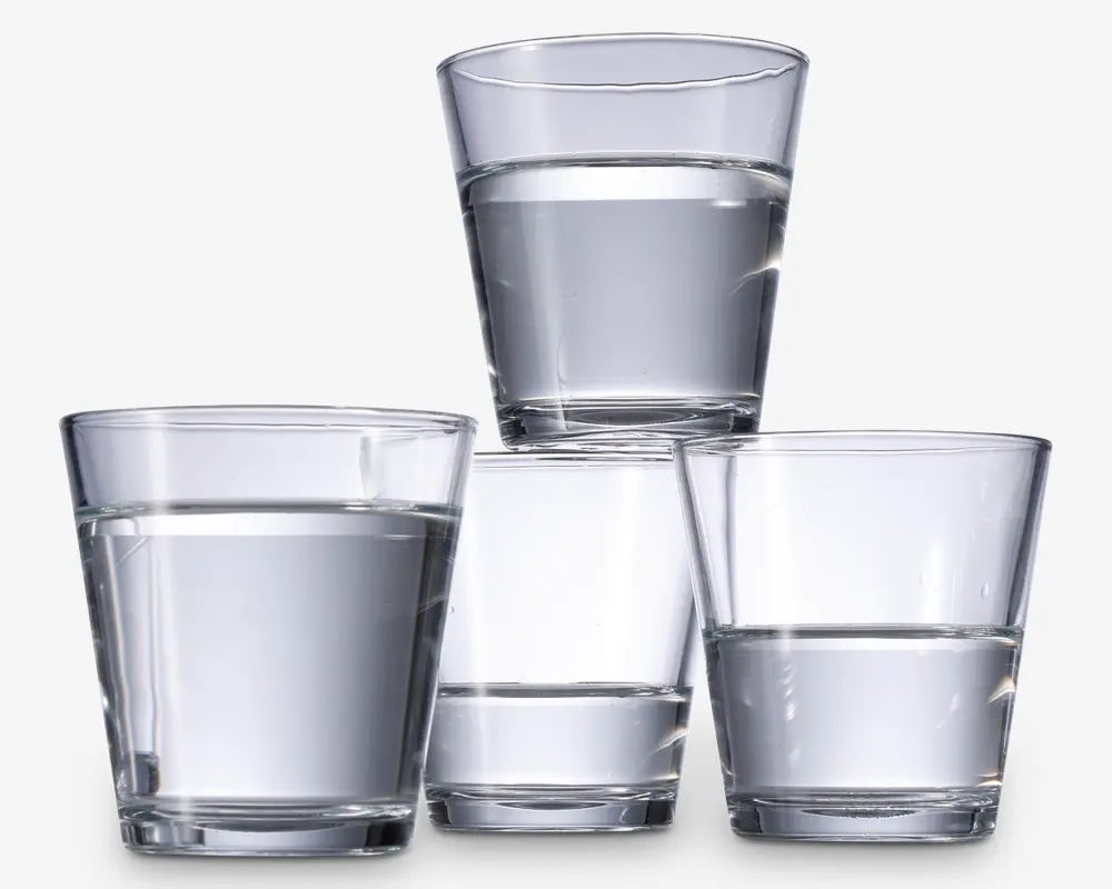 Fire klare, lave drikkeglas fyldt med vand. Glassene har en enkel, let konisk cylindrisk form med tykke bunde og er arrangeret med tre nederst og et ovenpå. Glasset er gennemsigtigt, så man tydeligt kan se vandet indeni.
