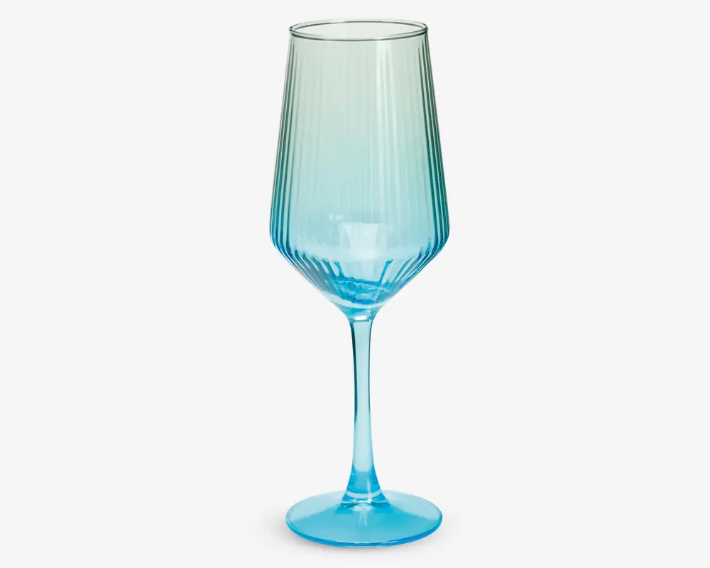 Høj, elegant glas med lang stilk og bred fod, der har en farvegradient fra klar øverst til livlig blå nederst. Glassets skål har lodrette rillede detaljer, som giver tekstur og et flot udtryk.