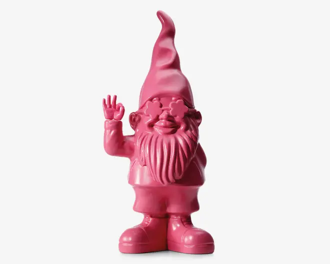 En dekorativ figur formet som en nisse, fuldstændig dækket af en blank pink overflade. Nissen har en høj, spids hat, et fyldigt skæg og store støvler. Den smiler og vinker med højre hånd, mens dens øjne er dækket af stjerneformede briller, hvilket giver et legende og finurligt udtryk.