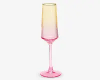 Højt, slankt glas med fløjteformet skål, der har et farveforløb fra lys gul øverst til kraftig pink ved bunden og stilken. Glasset har en glat, blank overflade og en solid rund fod for stabilitet.