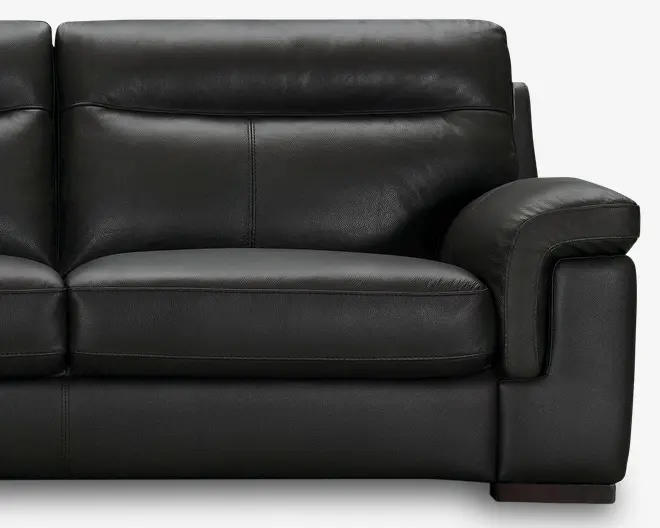 Nærbillede af et moderne sort lædersæde med bløde, fyldige hynder og brede, polstrede armlæn. Betrækket har en glat, let tekstureret overflade med synlige syninger, hvilket giver et stilrent og moderne udtryk.