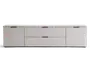 Moderne, lav opbevaringsenhed med mat lysegrå finish. Enheden har to store centrale skuffer med elegante sorte greb, flankeret af to skabslåger på hver side, også med matchende sorte greb. Designet er minimalistisk med rene linjer og en glat overflade, velegnet til moderne indretning.