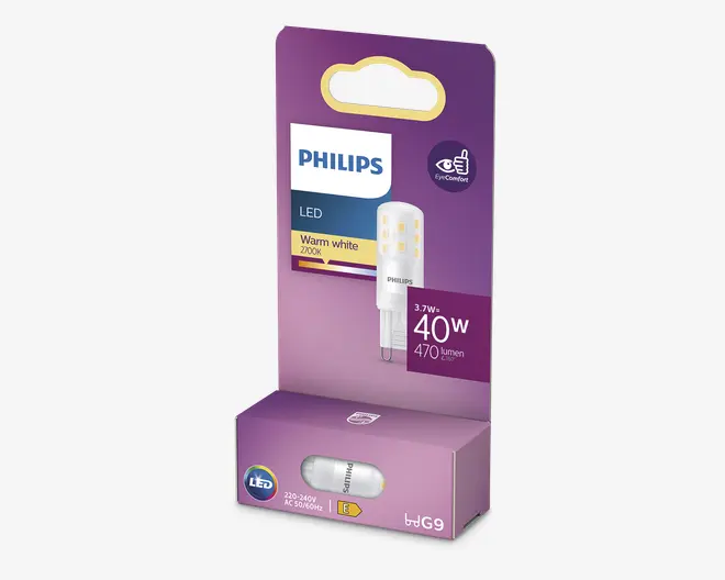En Philips LED-lyspære i G9 kapsel-form, pakket i en lilla æske. Pæren udsender et varmt hvidt lys ved 2700K, bruger 3,7 watt og giver 470 lumen, hvilket svarer til en traditionel 40-watts pære. Emballagen fremhæver 'EyeComfort' for behageligt lys og angiver kompatibilitet med 220-240V AC, 50/60Hz. Pæren kan ses gennem et lille vindue nederst på æsken.