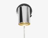 Væghængt lampe med cylindrisk form og blank kromfinish. Lampen har en rund base og en nedadrettet lyskilde med en klar linse i bunden. Designet er moderne og minimalistisk, velegnet til nutidige indretninger.