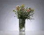 Høj, klar rillet glasvase med afrundet bund, fyldt med en løs buket af blandede vilde blomster i rosa, hvid, gul og grøn.