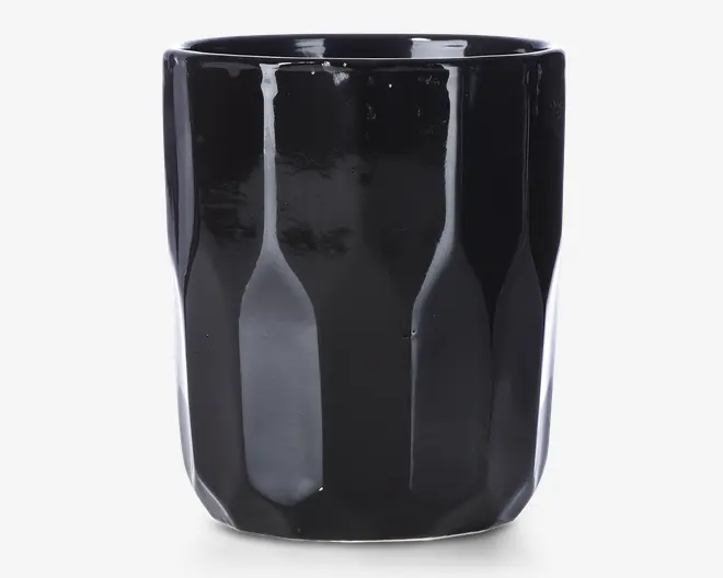 En blank sort keramikkop med en facetteret, geometrisk overflade. Koppen har en cylindrisk form med let tilspidsede sider og en glat kant. Den reflekterende finish giver et moderne og elegant udtryk.
